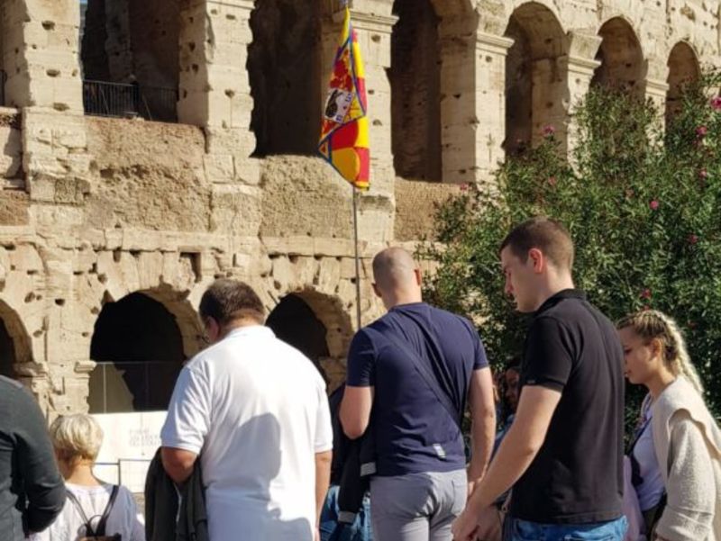 Turisti al Colosseo seguono la guida con la bandiera della Chiocciola